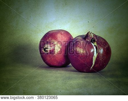 Two Entire (whole) Pomegranate Fruits Against Green Background With Grunge Filter Applied To Them- S
