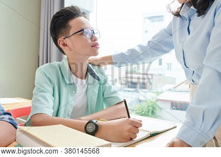 Teacher Patting Asian Schoolboy In Glasses On Shoulder And Praising Him For Progress In Math
