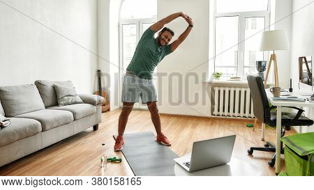 Personal Trainer. Full Length Shot Of Male Fitness Instructor Stretching His Body While Streaming, B