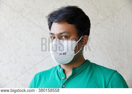 Adult Indian Man Wearing White N95 Mask In Green Round Neck T-shirt Looking Into The Camera And Look