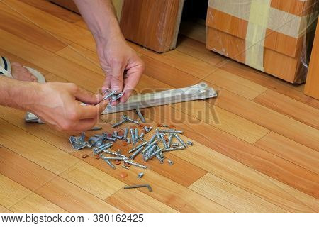 Man Prepared Bolts And Nuts For Collecting Furniture At Home, Closeup Hands. Man Takes Out The Bolts