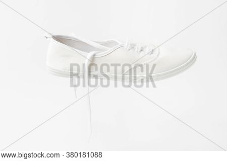 White Canvas Laced Unisex Plimsoll Shoe On Same Color Background With Copy Space. Classic Casual Spo