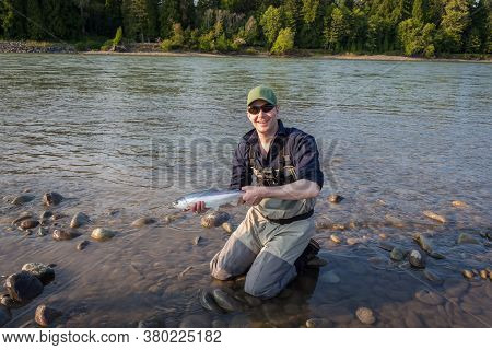 A Fisherman Holding Up A 'jack' Chinook Or King Salmon, Caught On The Skeena River, British Columbia