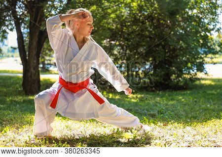 Young Woman Dressed In Kimono Practicing Her Karate Moves In Park - Red Belt