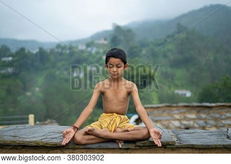 A Young Indian Cute Kid Doing Yoga In The Mountains,wearing A Dhoti