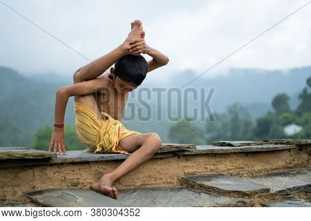 A Young Indian Cute Kid Doing Yoga In The Mountains,wearing A Dhoti