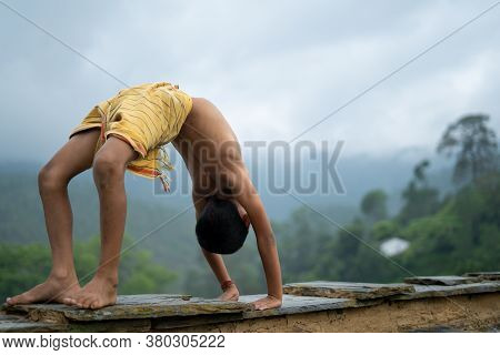 A Young Indian Cute Kid Doing Yoga In The Mountains,wearing A Dhoti