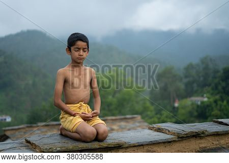 A Young Indian Cute Kid Doing Yoga In The Mountains,wearing A Dhoti