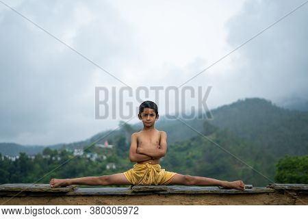 A Young Indian Cute Kid Doing Yoga In The Mountains,wearing A Dhoti