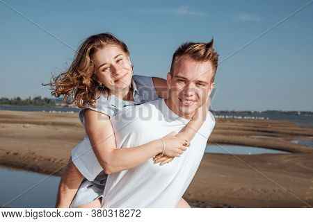 Couple In Love On The Beach.portrait Of A Couple In Love On The Beach. A Young Girl Hugs A Guy.