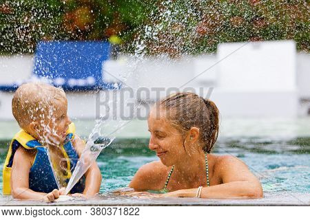 Happy People Have Fun At Pool Side Edge. Funny Photo Of Young Mother With Child Relaxing In Outdoor 