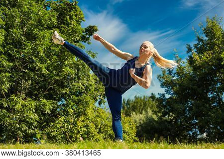 Young Woman Practicing Her Karate Moves In Park Red Belt