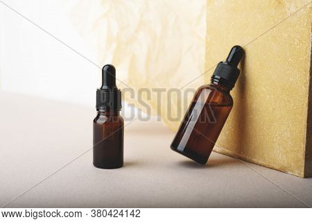 Serum Glass Bottles With Pipette Near Stone On Beige Wrinkle Paper Background.