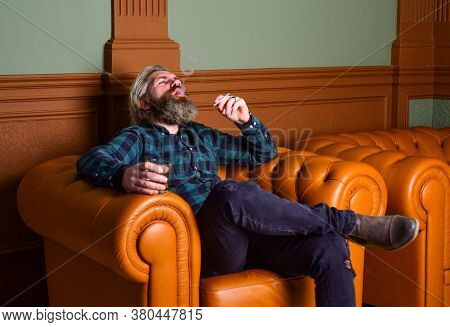 Confident Bearded Male Sit In Luxury Leather Armchair. Luxury And Success. Smoke Cigarette While Dri