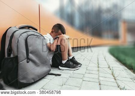 child with backpack in depression is sitting on the floor doesn't want back to school