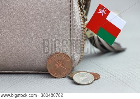 Heap Of Rial Omani Coin Money And Mini Oman Flag With The Leather Wallet On Grey Background. Concept
