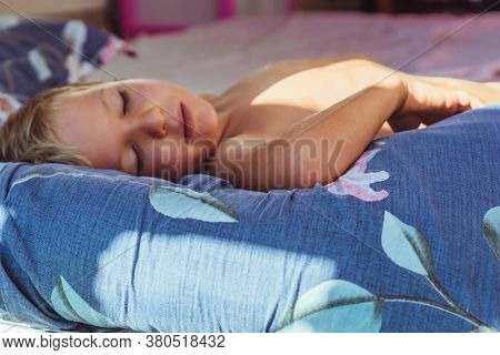 Cute Little Boy Sleep Sweetly On Pillow With Bright Morning Sunbeams From Window, Taking A Nap. Happ