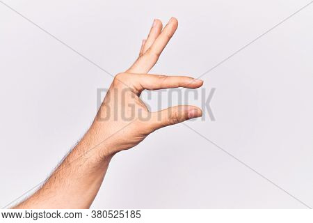 Close up of hand of young caucasian man over isolated background picking and taking invisible thing, holding object with fingers showing space 