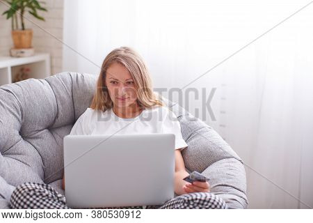 Realxed Beautiful Female Sits On Comfortable Sofa At Home, Holds Laptop Computer And Credit Card, Ma