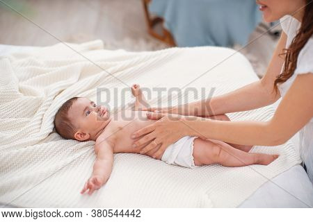 Baby Massage. Masseur Massaging Tummy Of Baby During Colic. Newborn Colicky Baby Without Clothes Lay