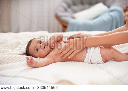 Baby Massage. Masseur Massaging Tummy Of Baby During Colic. Newborn Colicky Baby Without Clothes Lay