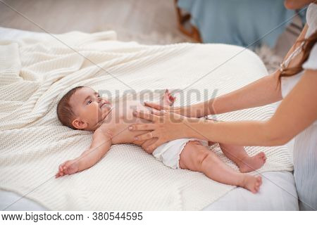 Baby Massage. Masseur Massaging Tummy Of Baby During Colic. Newborn Colicky Baby Without Clothes Lay