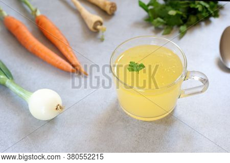 Bone Broth, Bone Stock In A Glass Cup And Vegetables  On The Background.  Paleo Diet. Horizontal,wit