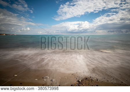 Seawaves Splashing Onto The Sandy Coast With Pebbles And Blue Cloudy Sky. Melanda Coast , Pissouri C