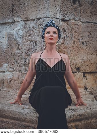 Beautiful Middle-aged Woman In Long Black Dress Sitting On The Stone Near Of Hidirlik Tower, Histori