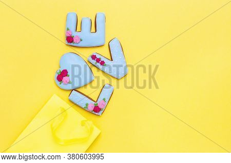 Inscription Love By Homemade Cookies And Yellow Package With Copy Space. Holiday Food Concept. Flat 