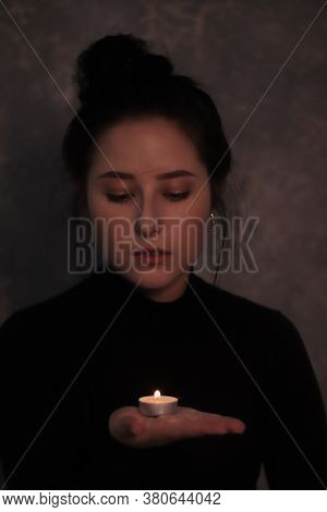 Dark Portrait Of A Sad Brunette Girl Almost Burst Into Tears In A Black Turtleneck Holding Candle Ag