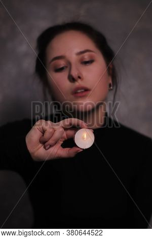 Dark Portrait Of A Sad Brunette Girl Almost Burst Into Tears In A Black Turtleneck Holding Candle Ag