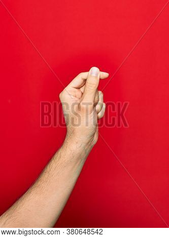 Beautiful hand of man showing fingers raised up doing money sign over isolated red background