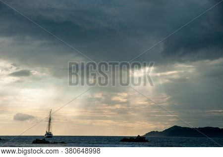 Dramatic Sky With Clouds And Sunbeam Over The Indian Ocean With Sailing Boat During Sunset.