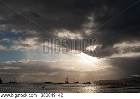 Dramatic Sky With Clouds And Sunbeam Over The Indian Ocean With Sailing Boat During Sunset.