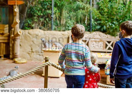 Two Kids Boys And Toddler Girl Visiting Together Zoo. Three Children Watching Animals And Insects. S