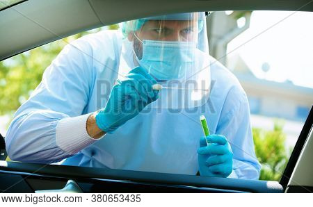Medical staff with PPE suit testing patient at a Covid-19 drive thru by throat swab. Health care drive thru service and medical concept