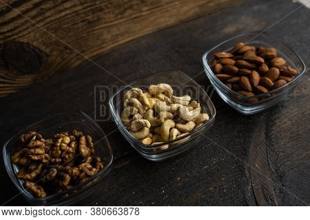 Almond, Cachew And Walnut In A Small Plates Which Standing On A Black Table. Nuts Is A Healthy Veget