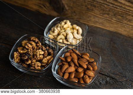 Almond, Cachew And Walnut In A Small Plates Which Standing On A Black Table. Nuts Is A Healthy Veget