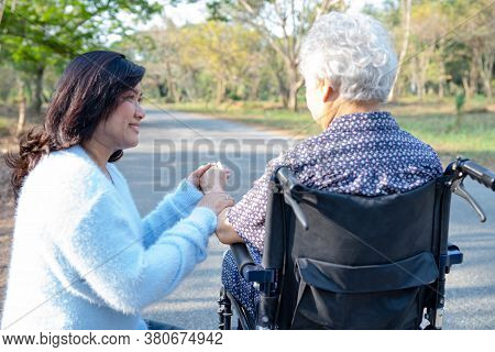 Help And Care Asian Senior Or Elderly Old Lady Woman Patient Sitting On Wheelchair At Park In Nursin