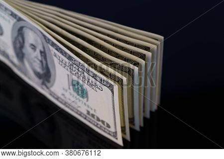 Fragment Of 100 Dollar Bills A On Black Glass. Close Up Of American Currency. Us Dollar Background. 