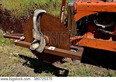 A Huge Rusty Saw Blade Is Mounted On A Tractor With A Leather Belt To Be Attached To The Belt Pulley
