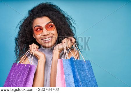 Dreamy Attractive Young Dark-skinned Woman With Curly Hair, Wearing Red Sunglasses, And A Sincere Ha