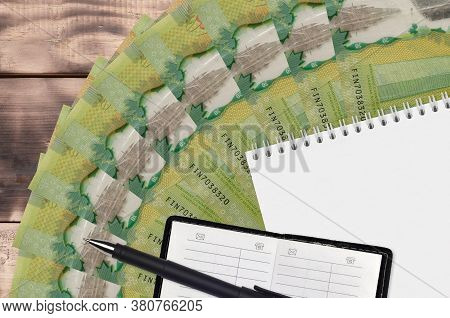20 Canadian Dollars Bills Fan And Notepad With Contact Book And Black Pen. Concept Of Financial Plan