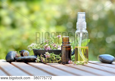 Bottles Of Essential Oil And Flowers Of Aromatic Herb On Atable And On Green Background
