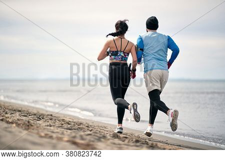 Male and female runner workingout on the beach