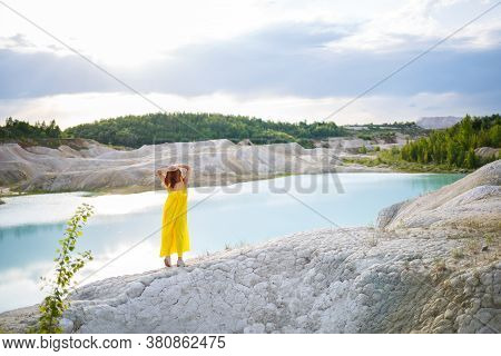 Young Woman Near A Lake With Azure Water And Stony Mountains With Green Trees. Beautiful View Of The