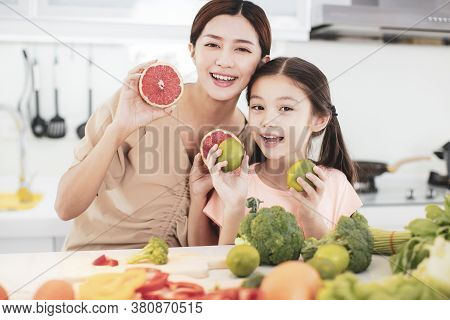 Happy Mother And Child Daughter  Preparing The Vegetables And Fruit