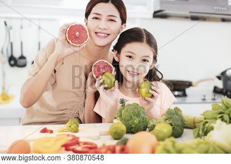 Happy Mother And Child Daughter  Preparing The Vegetables And Fruit In Kitchen