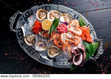 Assorted Seafood, Shrimp, Scallops, Squid, Mussels. Serving Plates On The Table With A Set Of Seafoo